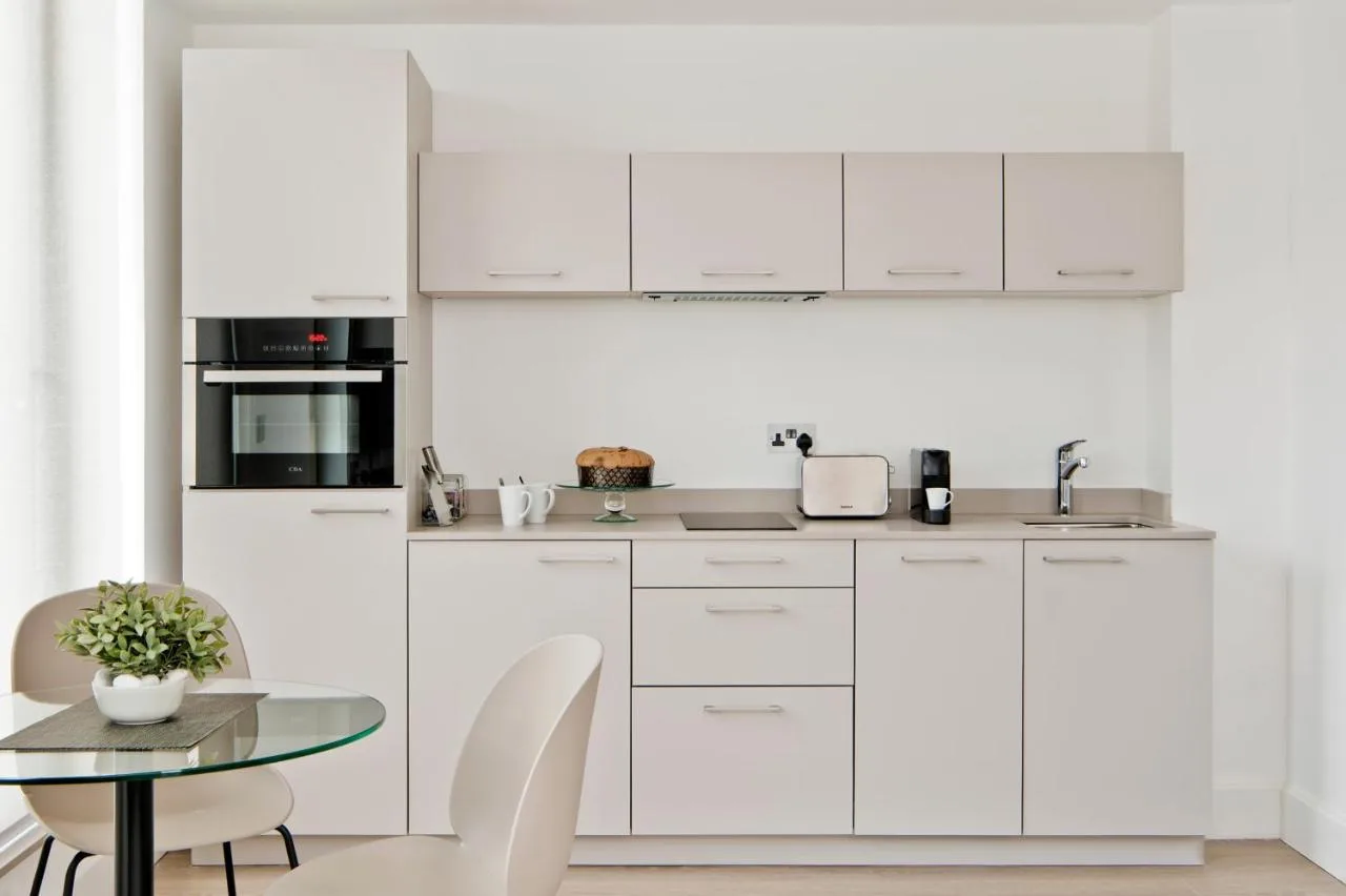 a kitchen with white cabinets and a table at Micklegate by Supercity Aparthotels in York