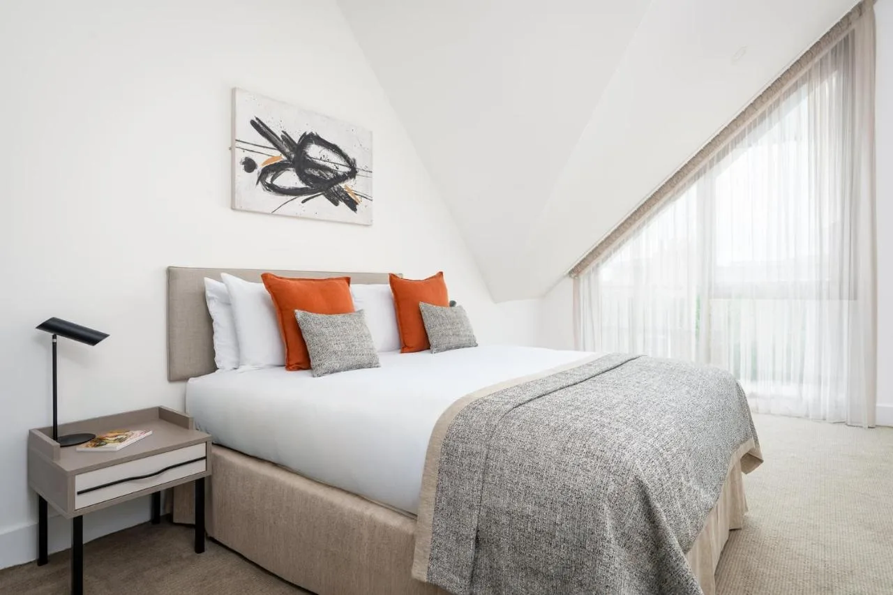 a white bedroom with a large bed with orange pillows at Micklegate by Supercity Aparthotels in York
